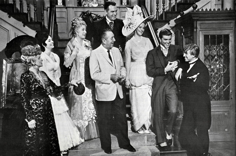 Walt Disney, center, photographed with the cast of “The Happiest Millionaire” on set. Fred MacMurray, who portrayed the titular character and Anthony J. Drexel's grandson, stands behind him. 